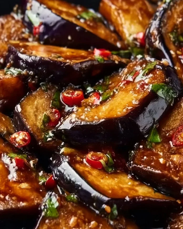 Delicious sticky garlic eggplant served on a plate, garnished with herbs.