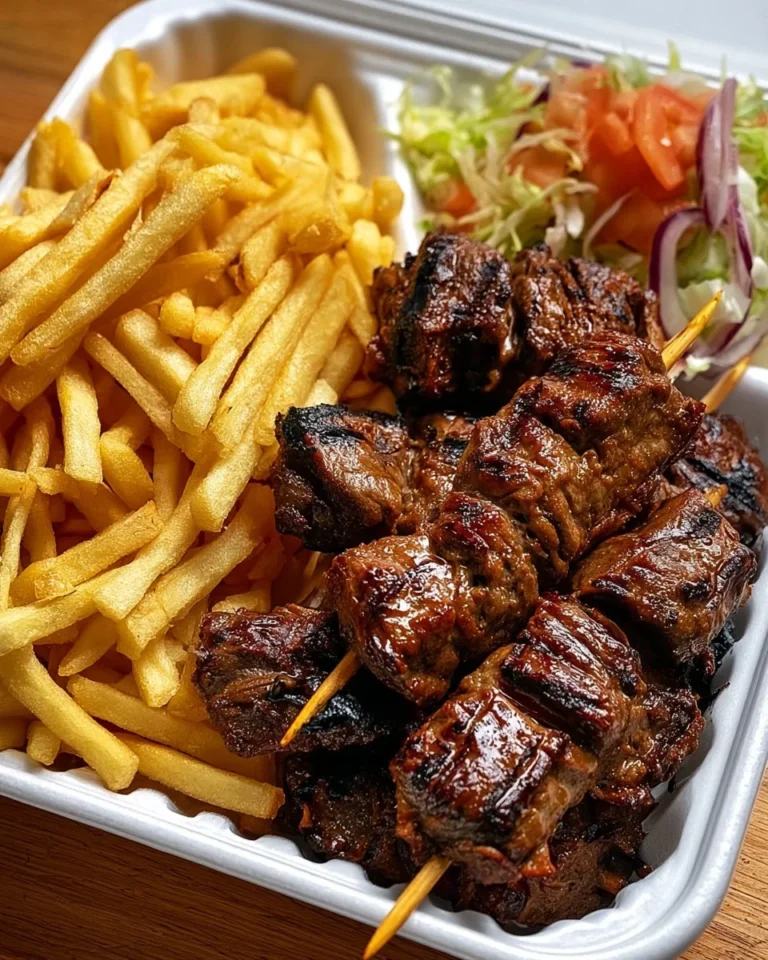 Grilled beef skewers served on a plate, garnished with fresh vegetables.